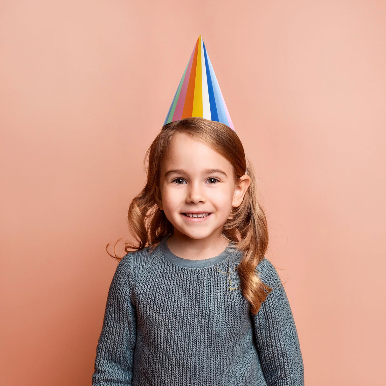 Child wearing rainbow paper party hat