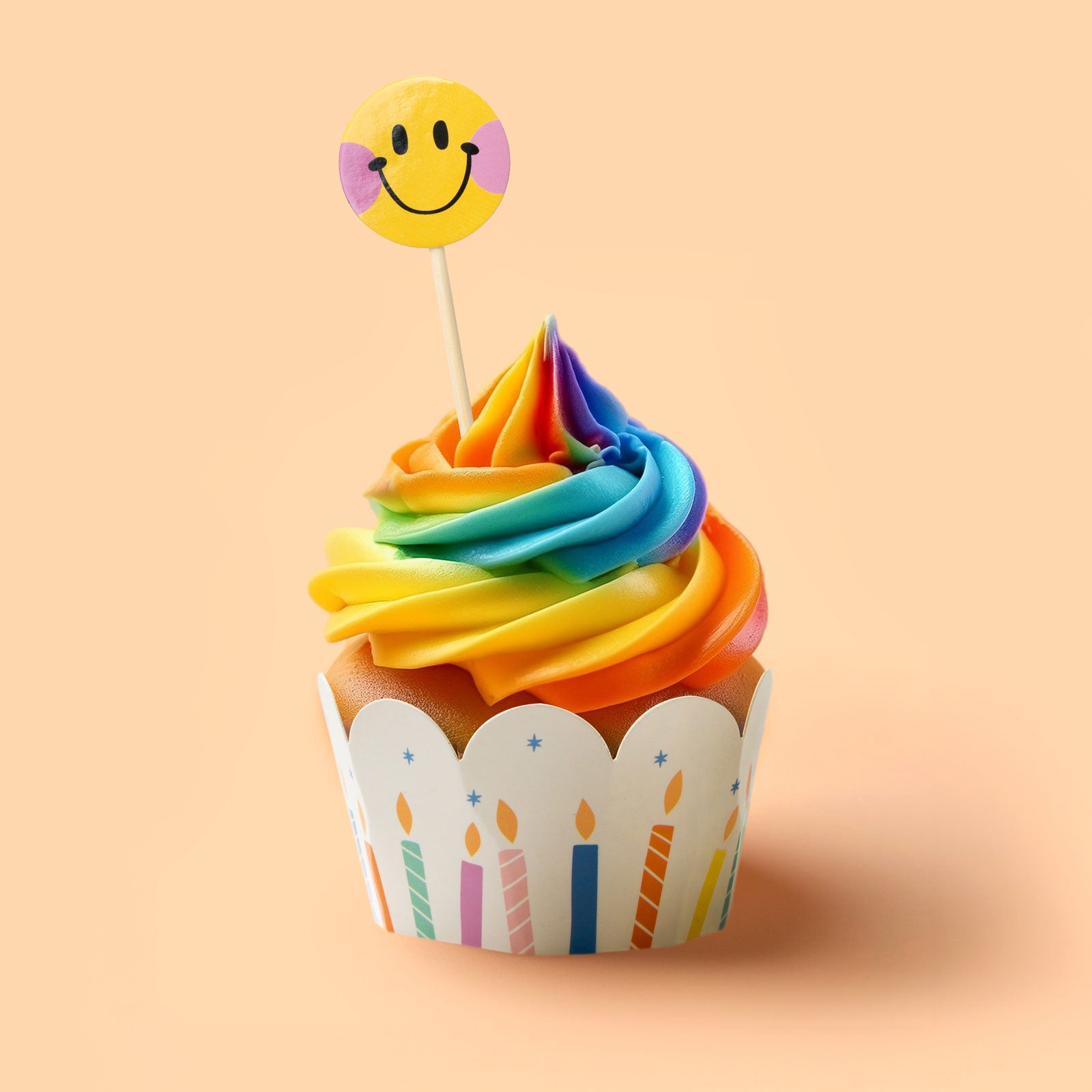 Rainbow cupcake with decorative lining and stick in smiley face
