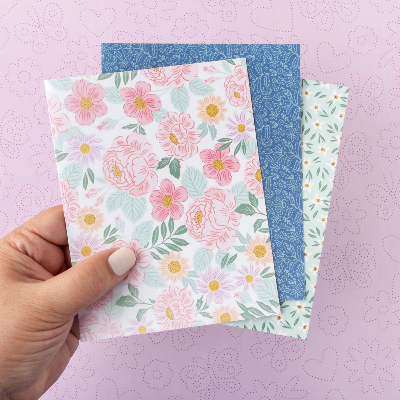 Lifestyle image of a person holding three different cards offered with the American Crafts Sketchbook Bea Valint Boxed Cards - 40 Pack