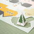A piece of the Crate Paper Holly Jolly Holiday Village 12 x 12 Cardstock Specialty Paper - 15 Pack that is folded