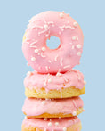 Load image into Gallery viewer, Lifestyle image of pink glazed Sweetshop Vanilla Cake Donuts with white sprinkles
