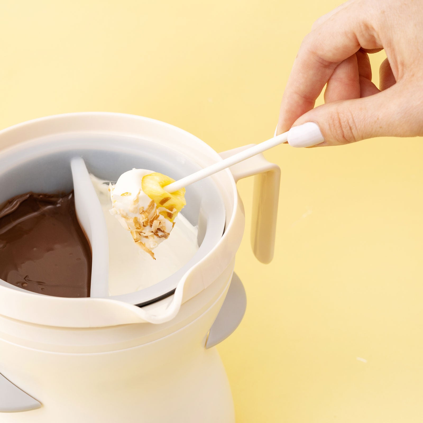 Lifestyle image of AC Sweetshop Dual Chocolate Melting Pot with pineapple being dipped into white chocolate