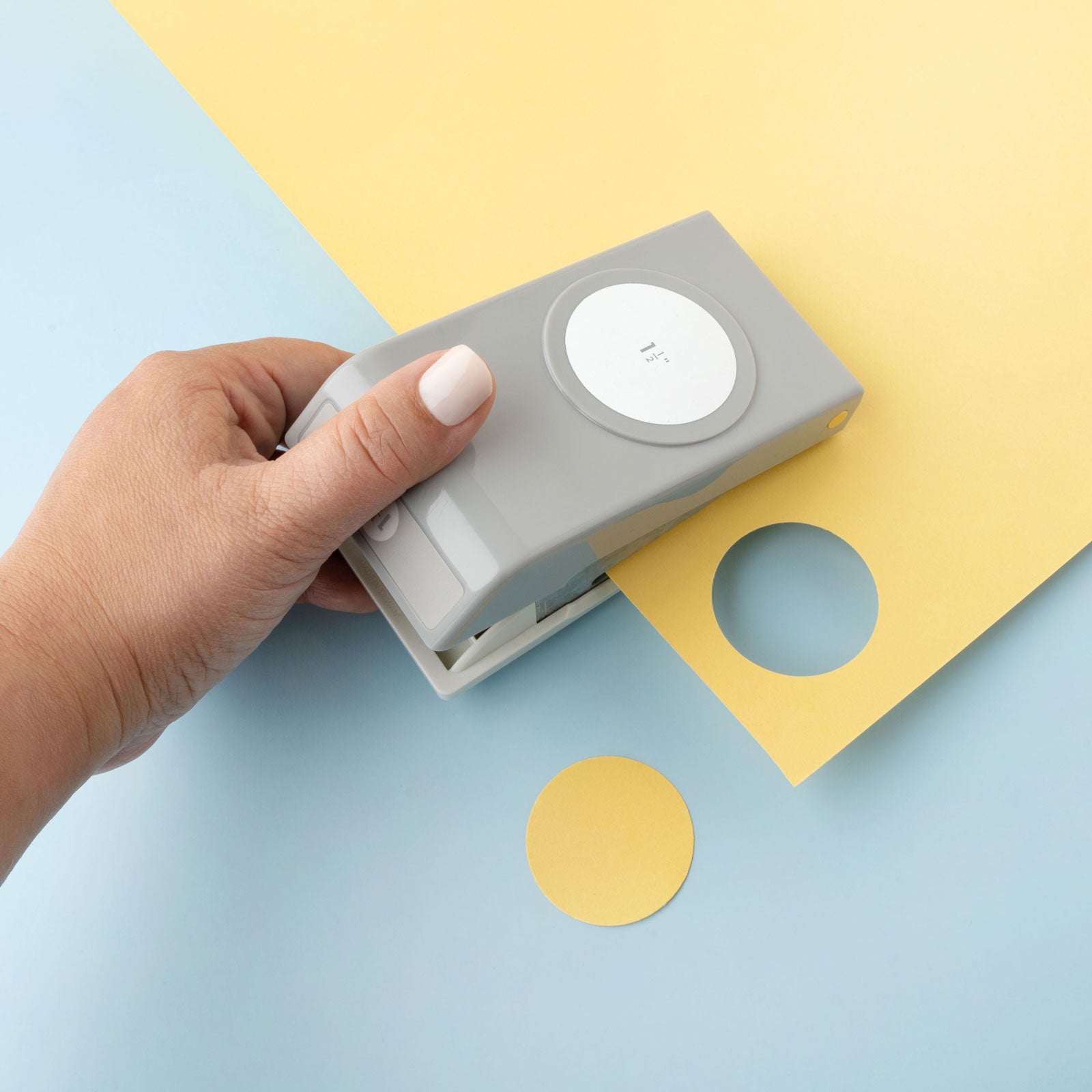 Lifestyle image of EK Tools 1 1/2 Inch Circle Paper Punch being used on yellow paper