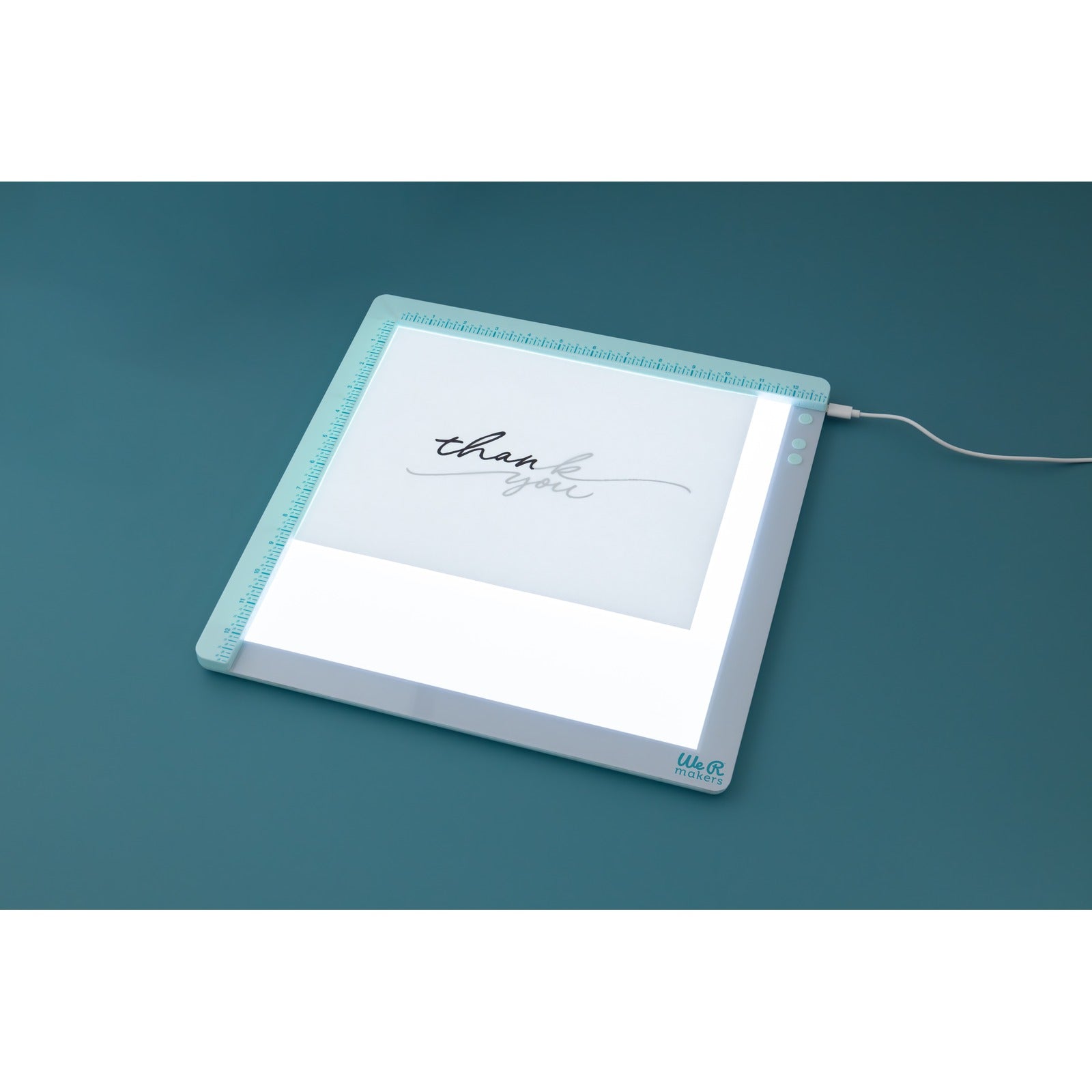 Lifestyle image of We R Makers Edge Align Light Pad being used to trace thank you