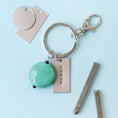 Load image into Gallery viewer, Lifestyle images of keychain with jewelry piece that is stamped
