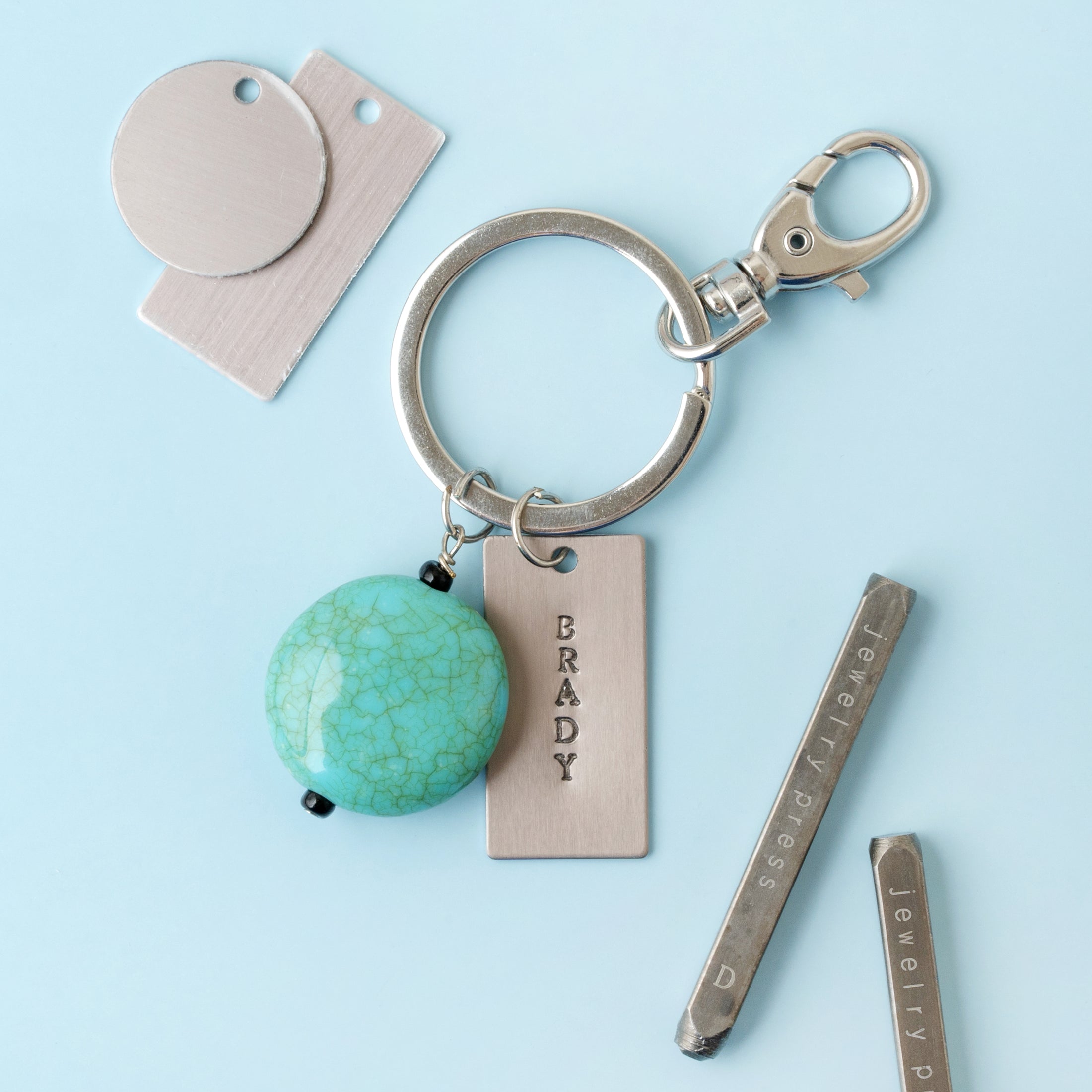 Lifestyle images of keychain with jewelry piece that is stamped