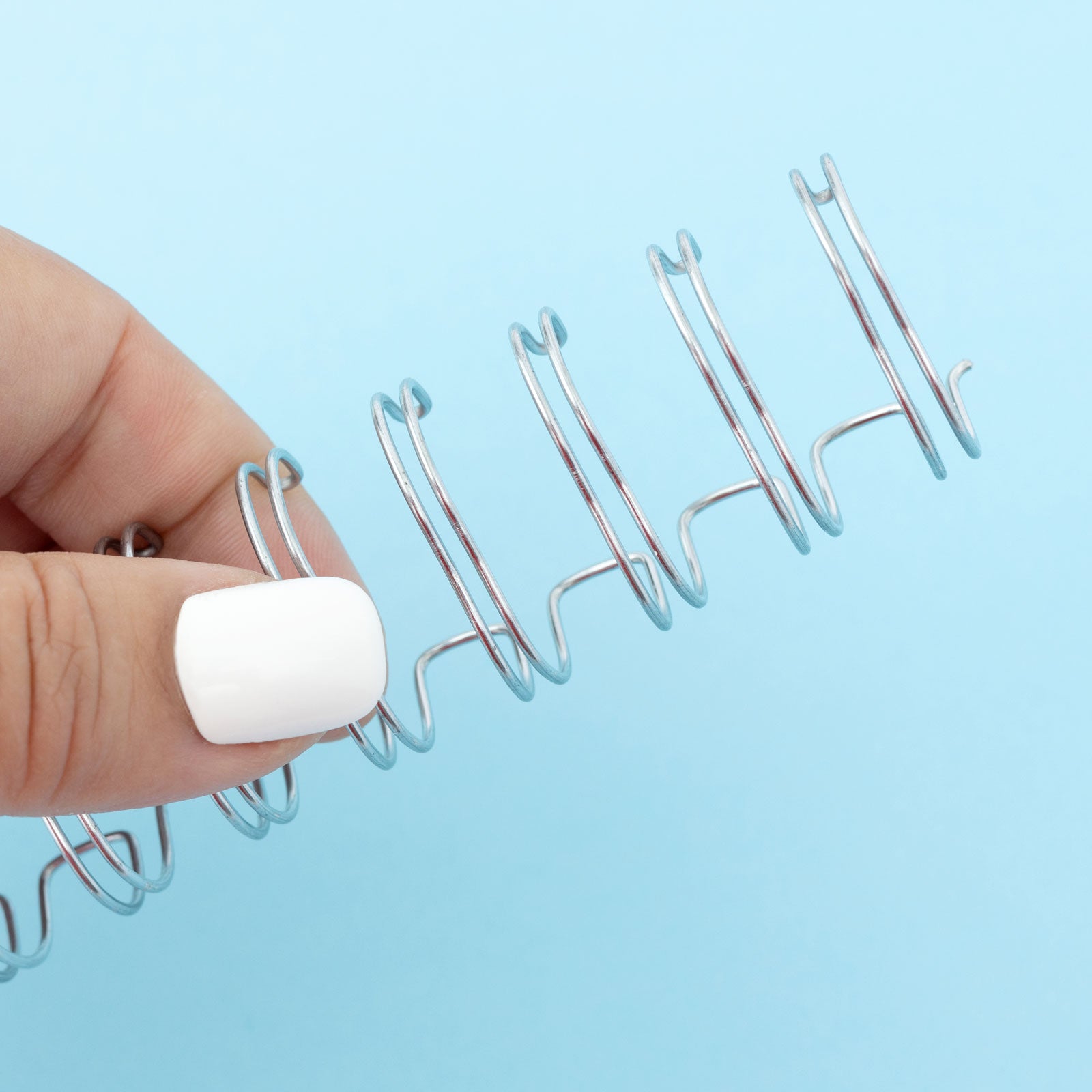 Lifestyle image of We R Makers Cinch Book Binding Silver Wire being held showing close up