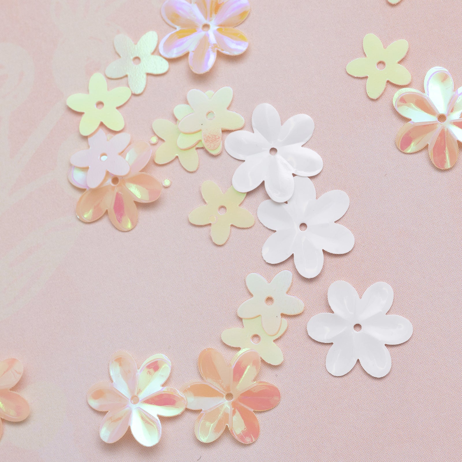 Pastel-colored flower-shaped sequins on a pink background