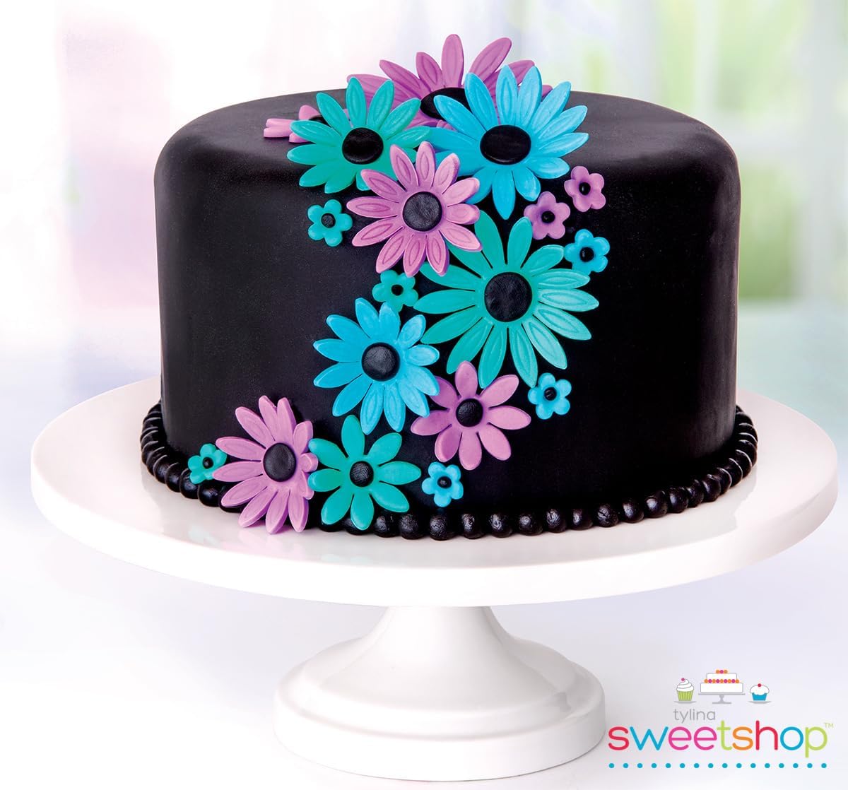 Picture of a black cake with neon flowerws on it.