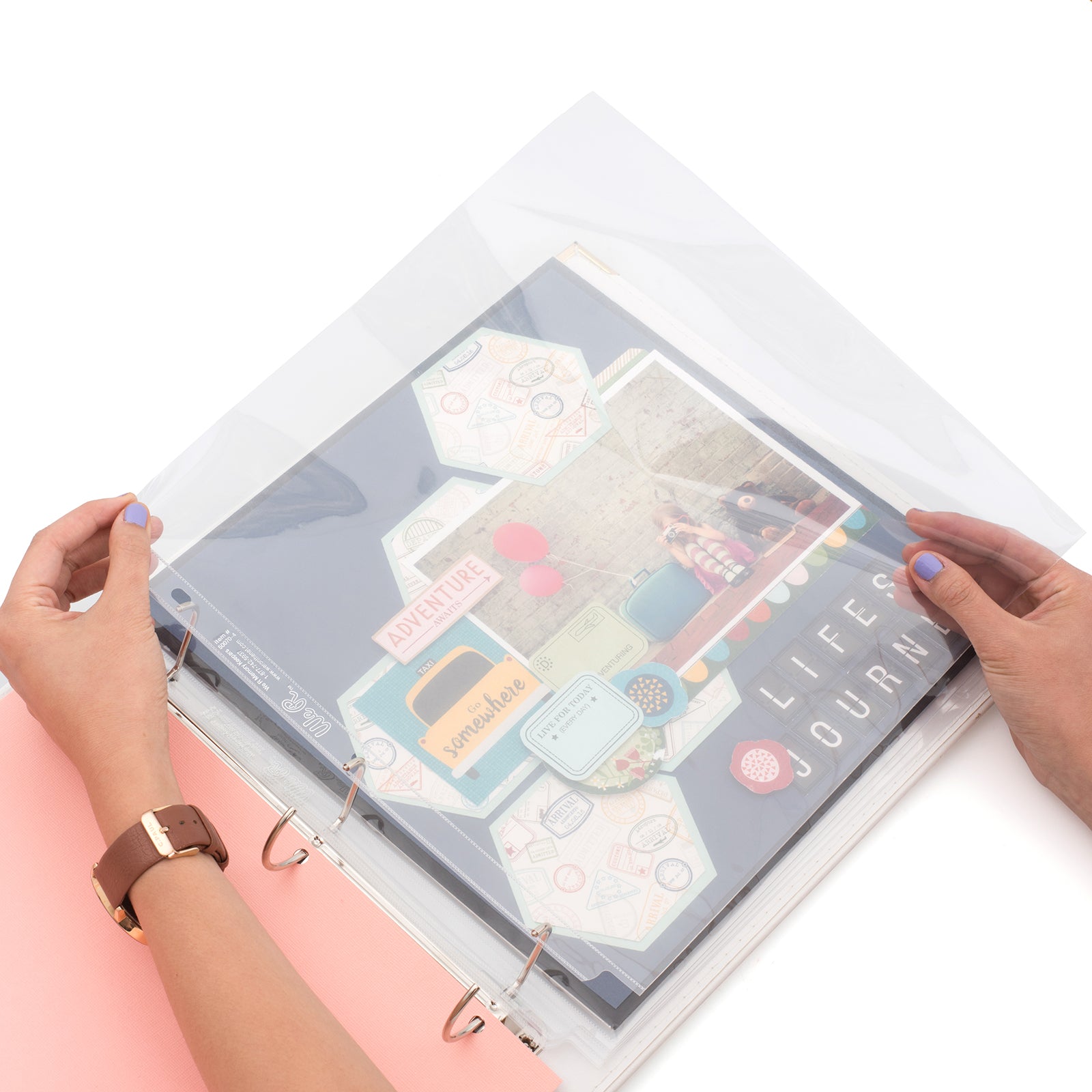 A person using the We R Makers 12x12 Non-Glare Page Protectors for a binder.