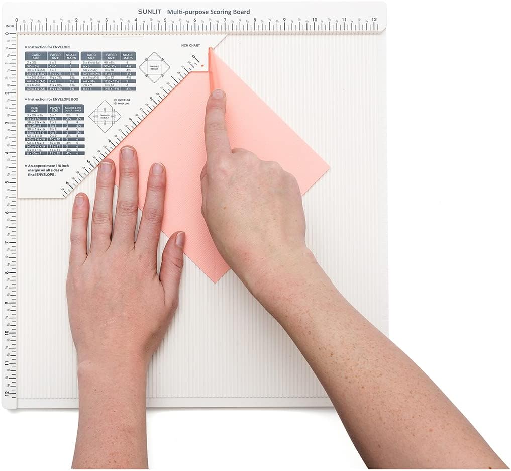 A person using the We R Makers Basic Trim & Score Board to cut paper. 