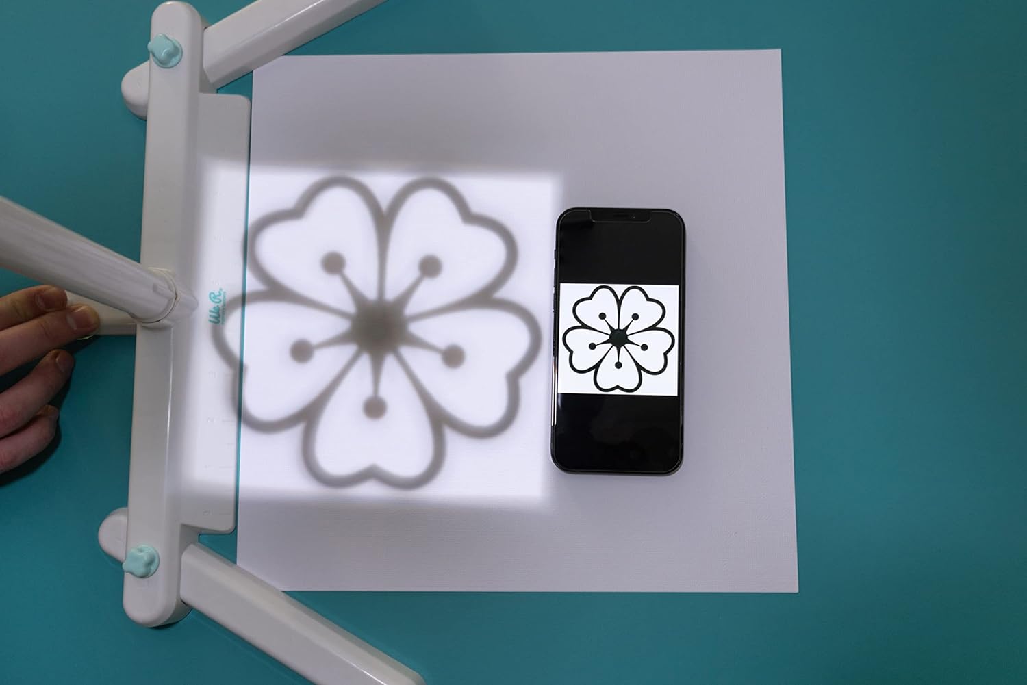 Image of a flower stencil being projected by the We R Makers Craft Projecter Tool.