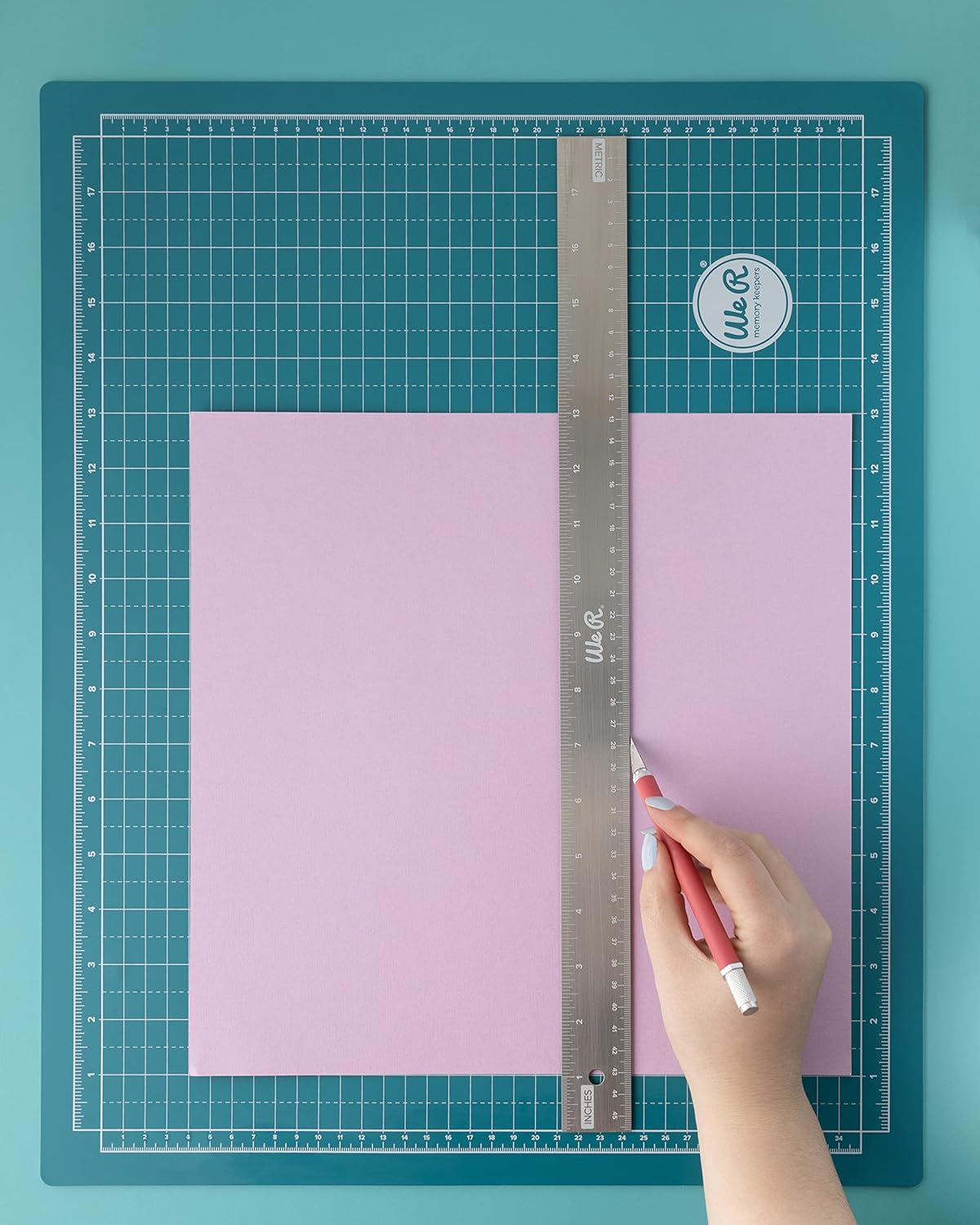 Picture of a person using the We R Makers Large 18x14 Magnetic Mat to draw a line with a ruler.