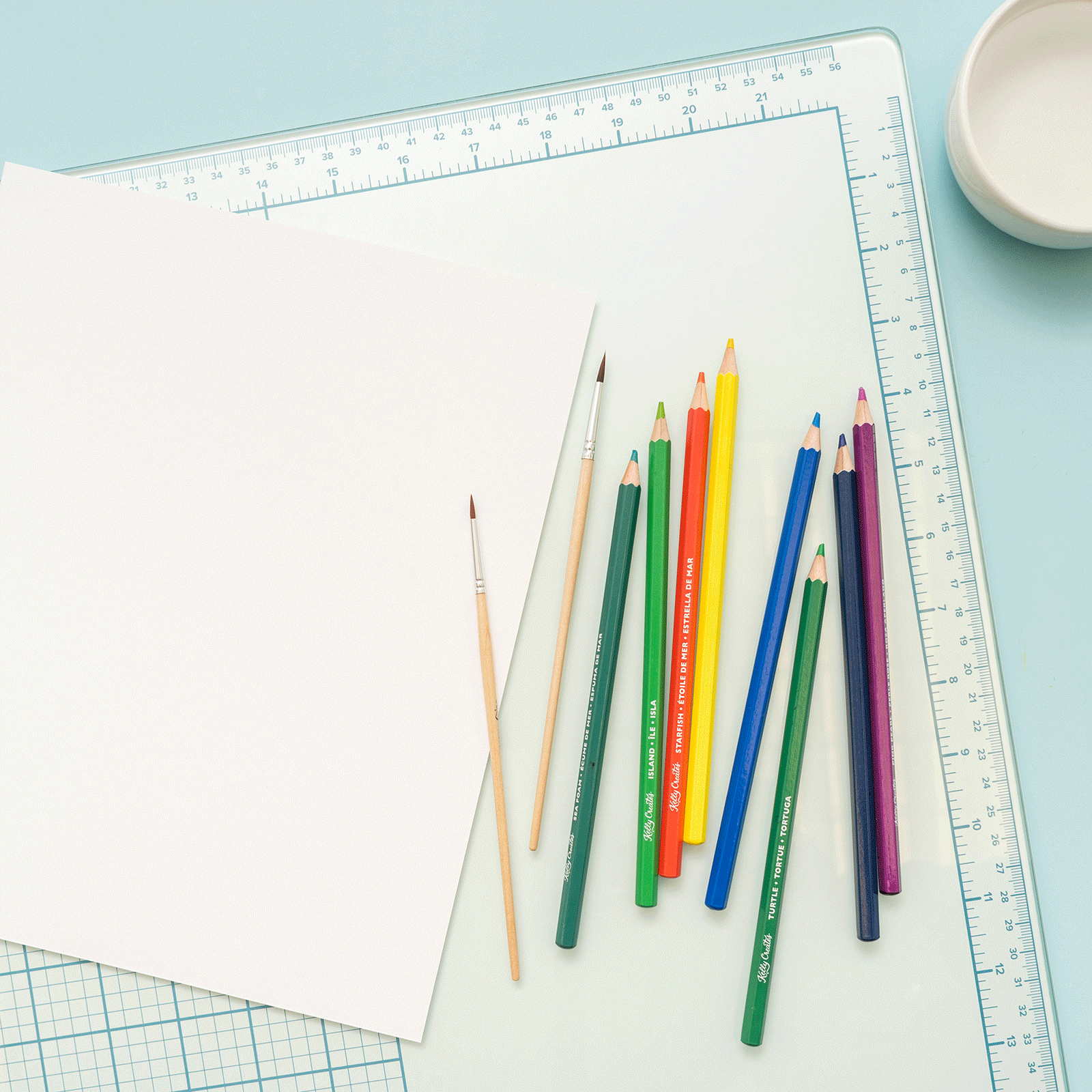 Picture of a person with colored pencils on the We R Makers Mixed Media 16x22 Glass Mat.