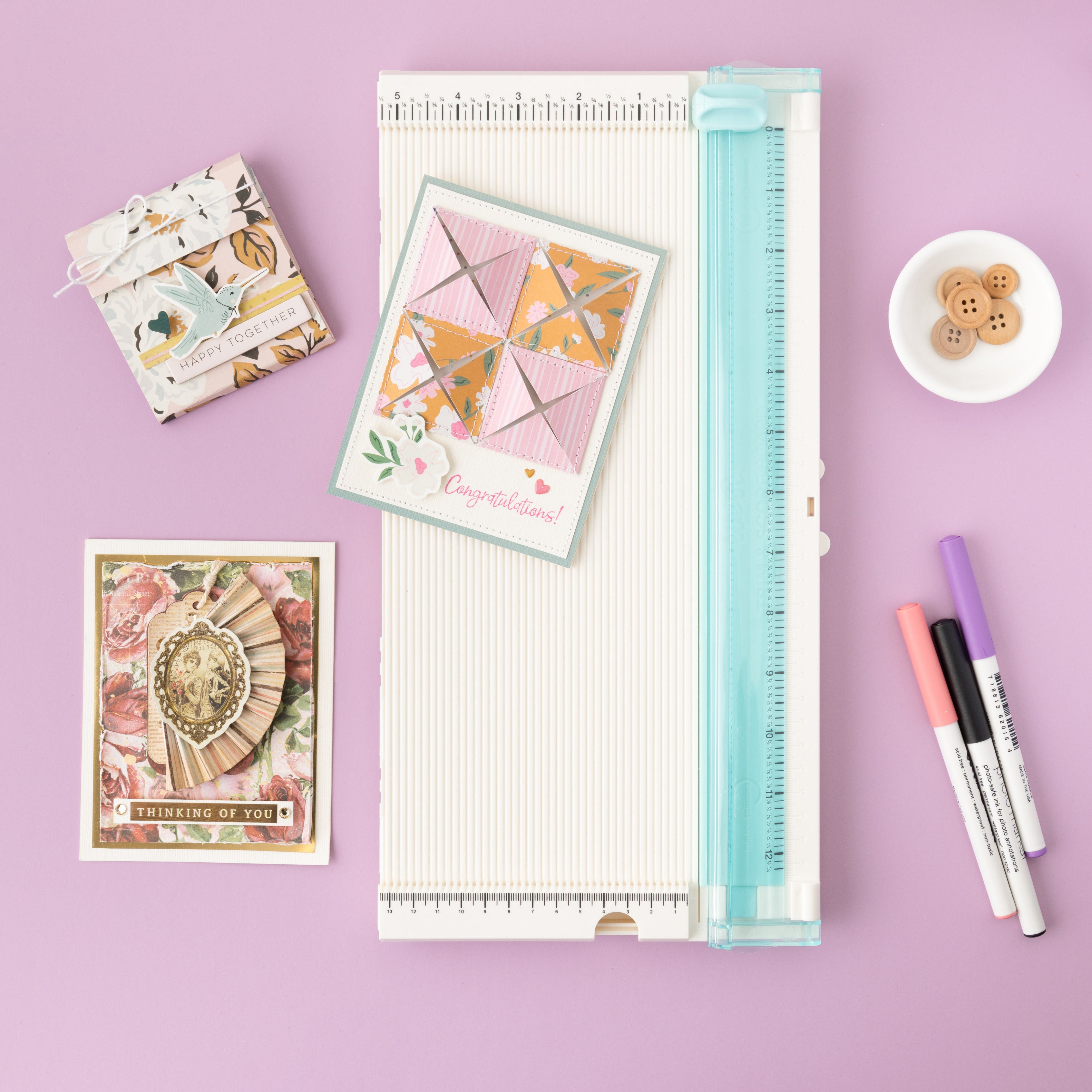 Lifestyle image of the We R Makers Trim & Score Board with Two Titanium Blades along with crafts.